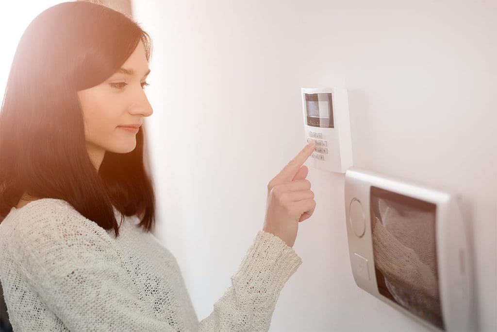 a woman adjusting a digital thermostat