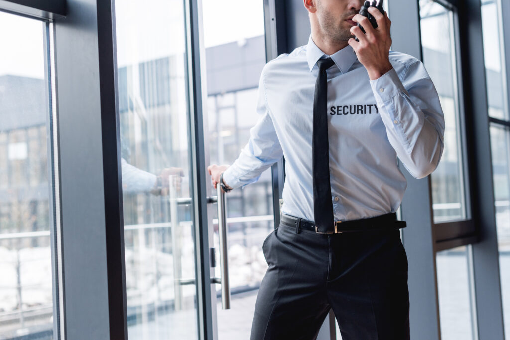 cropped view of handsome guard in suit talking on walkie-talkie